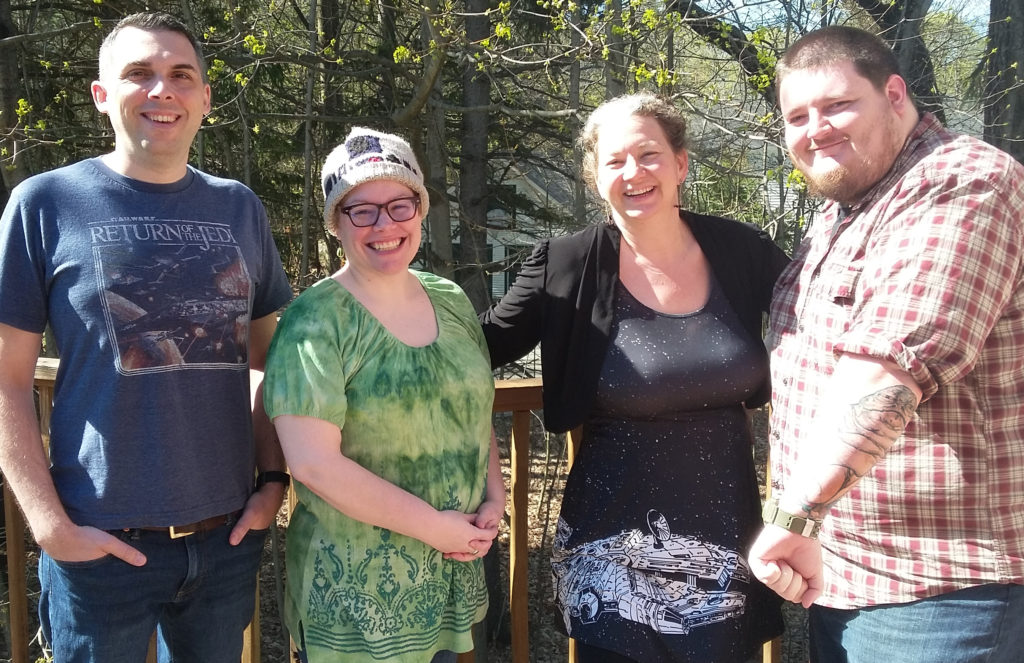 Four members of the RainStorm staff wearing Star Wars related clothing and items stand in the sunlight